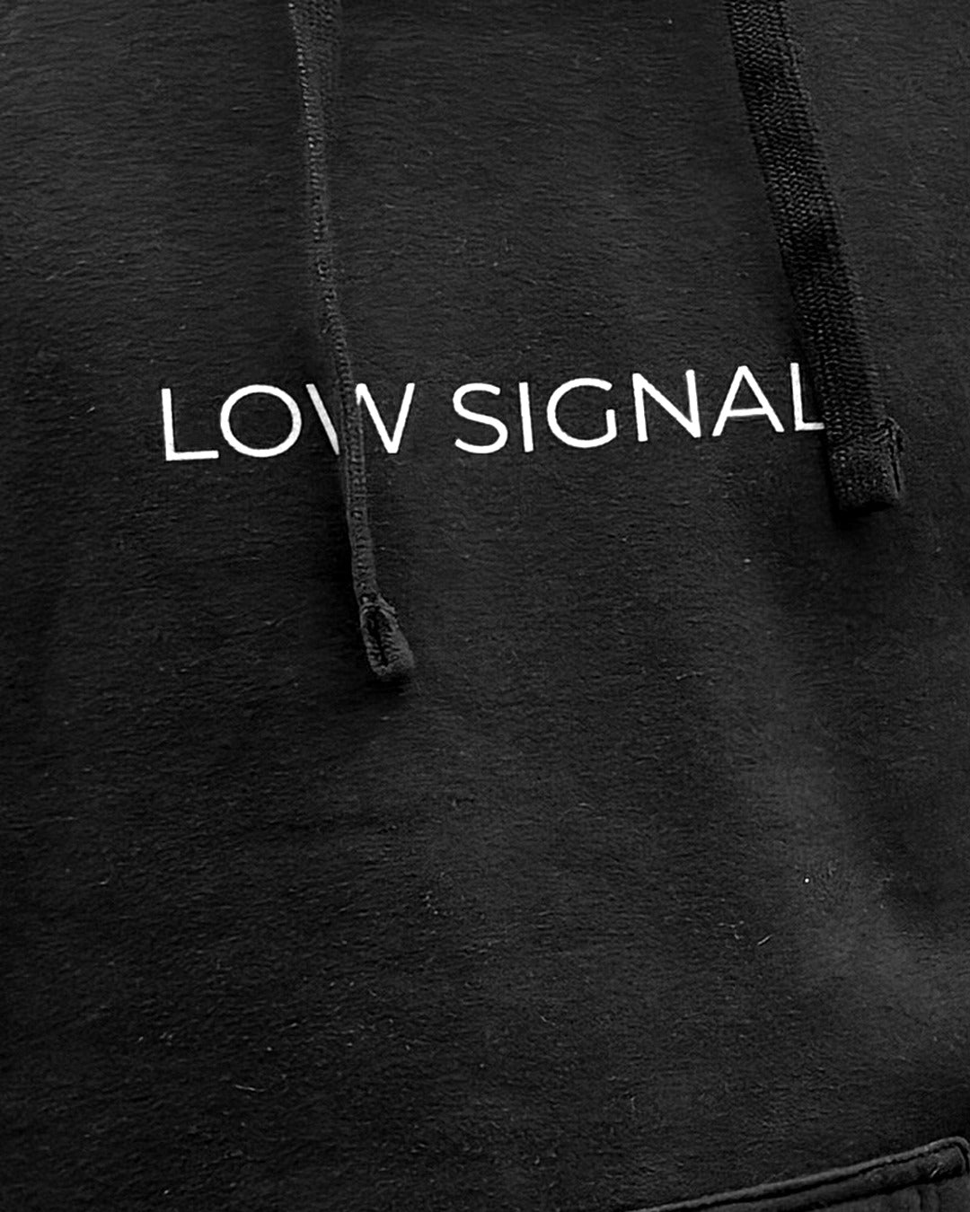 LOW SIGNAL CORE Hoodie in Carbon Black, close-up of the chest wordmark