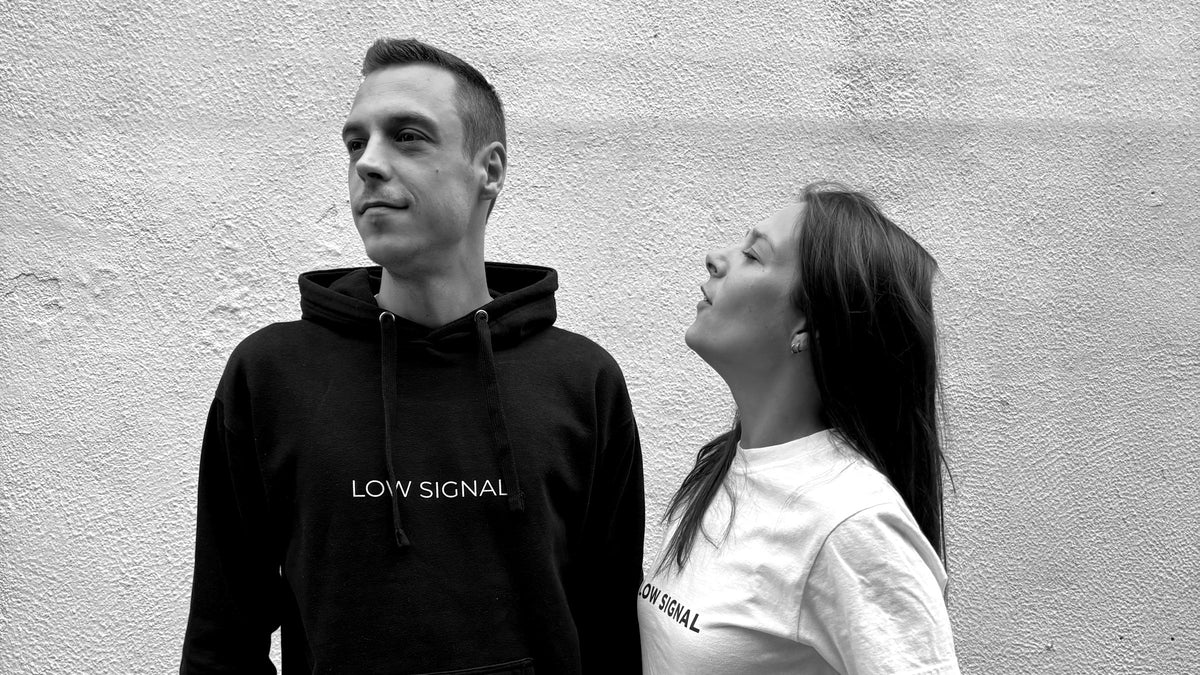 LOW SIGNAL CORE Hoodie in Carbon Black and CORE Tee in Matte White against a white wall, black and white