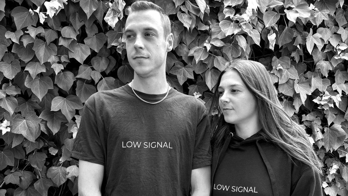 Two people wearing LOW SIGNAL heavyweight cotton streetwear, black and white